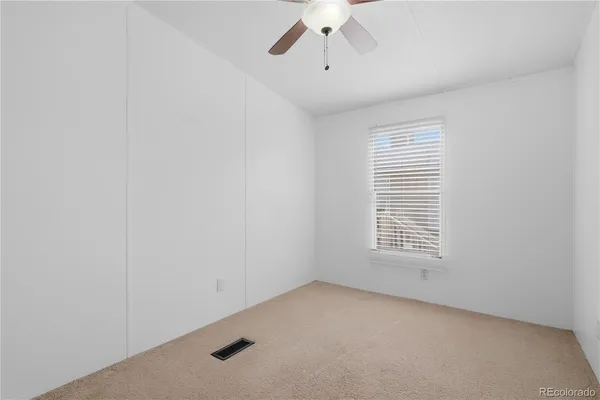 an empty room with a window and a ceiling fan