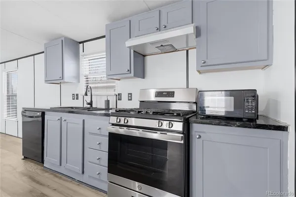a kitchen with granite countertop white cabinets and appliances