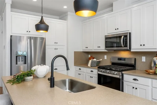 a kitchen with stainless steel appliances granite countertop a dining table chairs stove and refrigerator