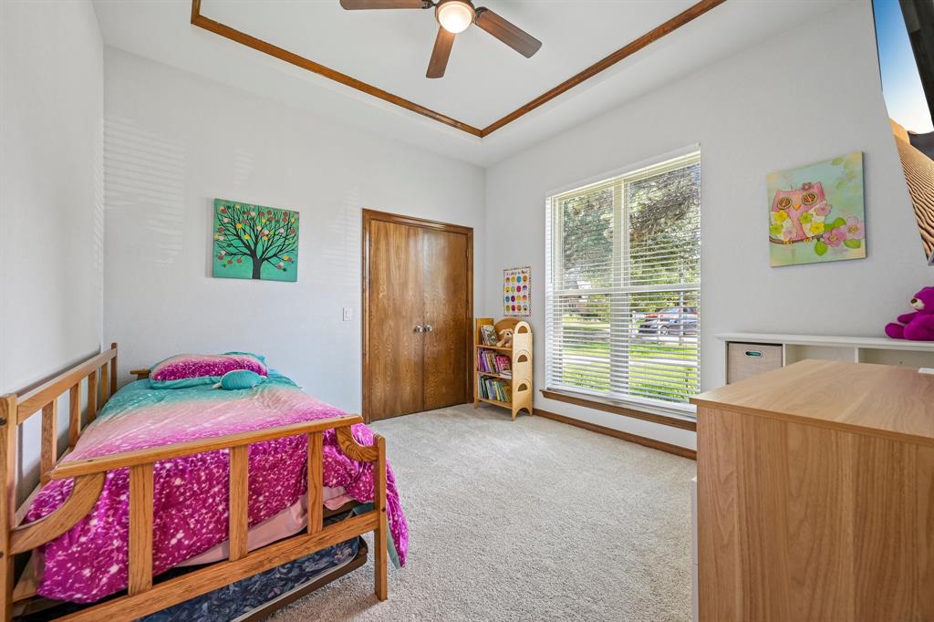 925 Spring Brook Drive Allen, TX 75002 - Photo 17 of 30 Bright bedroom featuring wood-frame twin bed, carpeted flooring, vaulted ceiling with ceiling fan, large sliding glass doors with natural light, and wood-finish dresser with storage