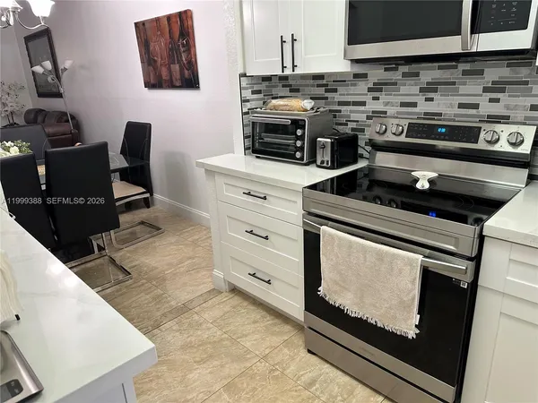 a kitchen with white cabinets and appliances