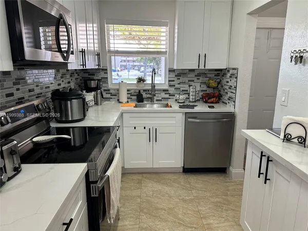 a kitchen with stainless steel appliances a sink a stove a refrigerator a counter space and cabinets
