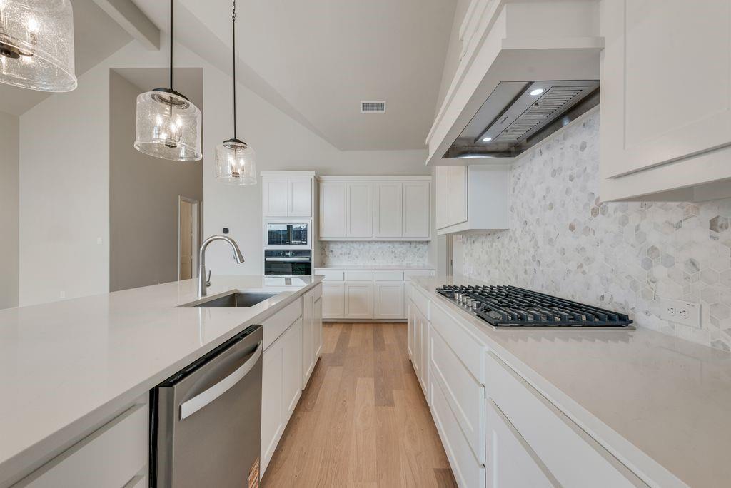 1259 Calebria Way Fate, TX 75087 - Photo 11 of 38 a kitchen with stainless steel appliances a sink dishwasher a stove and a refrigerator with wooden floor