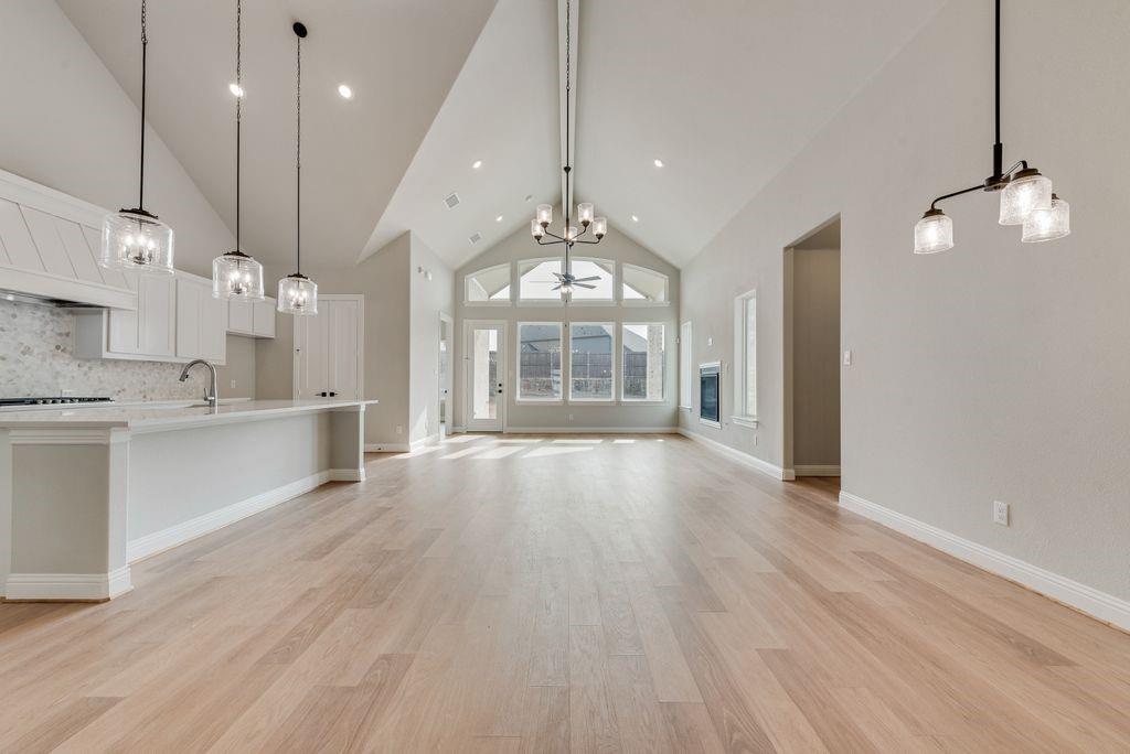 1259 Calebria Way Fate, TX 75087 - Photo 4 of 38 a open kitchen with kitchen island a stove a refrigerator a sink dishwasher and a dining table with wooden floor