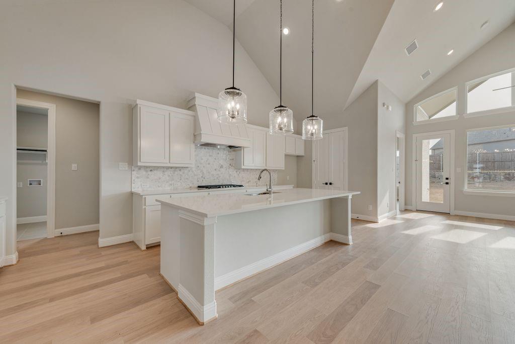 1259 Calebria Way Fate, TX 75087 - Photo 9 of 38 a large kitchen with kitchen island a white counter space a sink and appliances