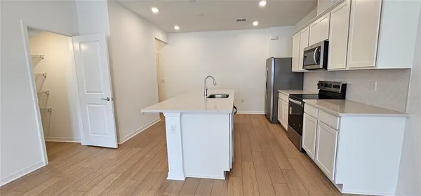 a kitchen with stainless steel appliances granite countertop a refrigerator a stove top oven and wooden floor
