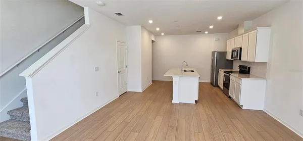 a view of a kitchen center island wooden floor and stainless steel appliances