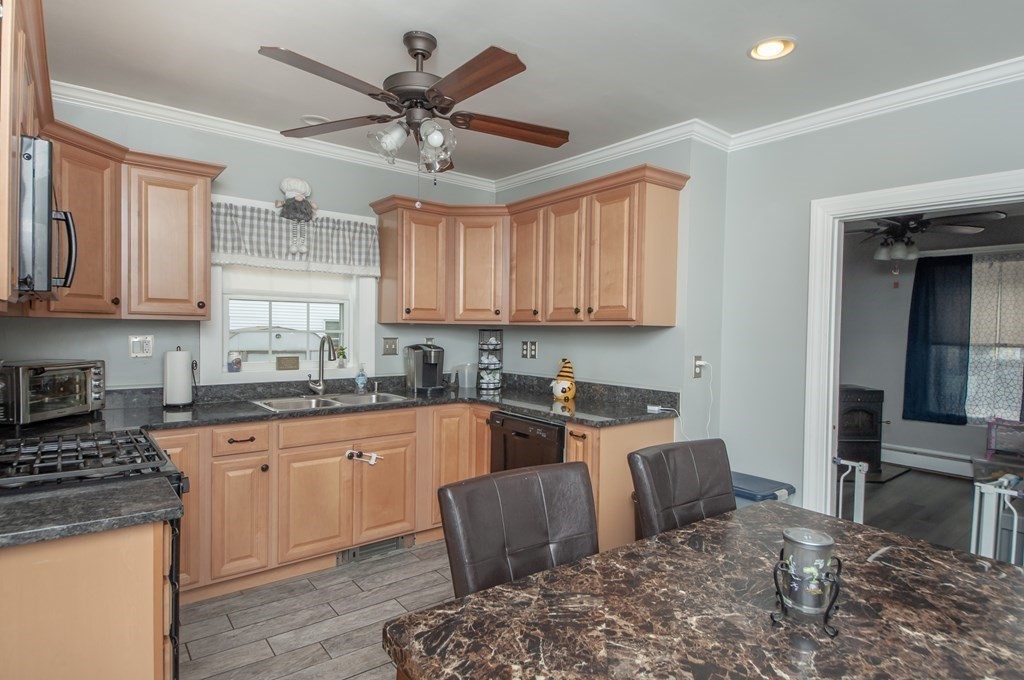 4 Fay Place Haverhill, MA 01830 - Photo 3 of 25 a kitchen with stainless steel appliances granite countertop a stove top oven a sink a dining table and chairs with wooden floor