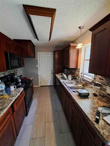 a kitchen with stainless steel appliances granite countertop a sink stove and wooden cabinets