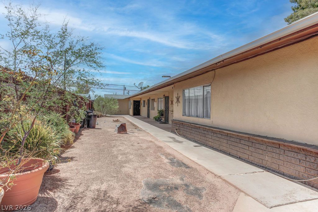 421 North Decatur Boulevard, Unit 2 Las Vegas, NV 89107 - Photo 4 of 21 A desert-friendly landscape surrounds this stucco-finished structure with brick detailing, offering a functional outdoor space.