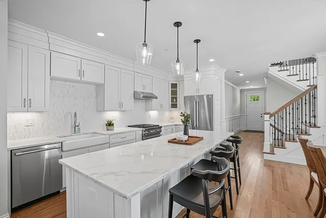 a kitchen with stainless steel appliances kitchen island a table chairs and a refrigerator