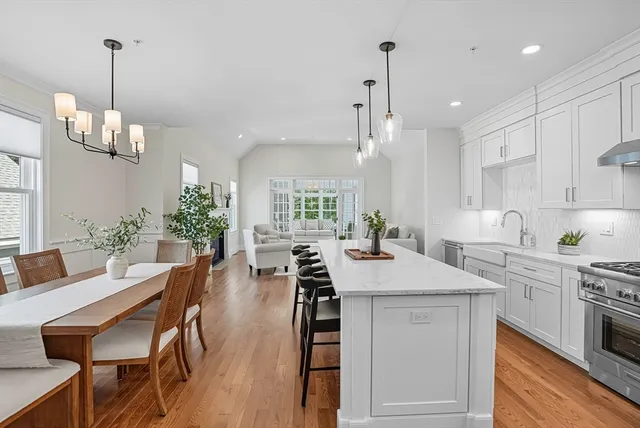 a kitchen with stainless steel appliances kitchen island a table chairs in it and white cabinets
