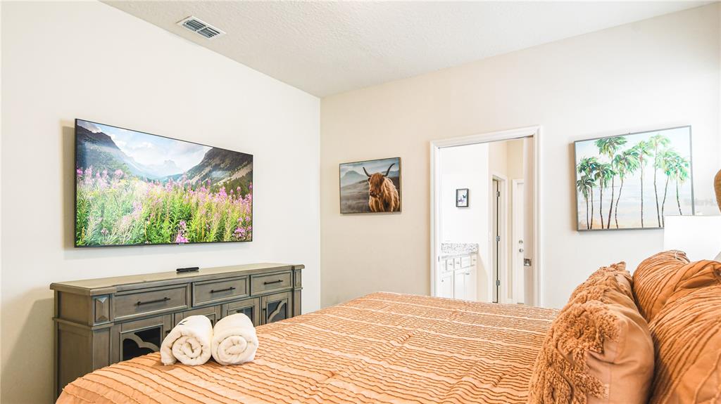 7219 Oakmoss Loop Davenport, FL 33837 - Photo 16 of 54 a bedroom with a bed and a flat screen tv