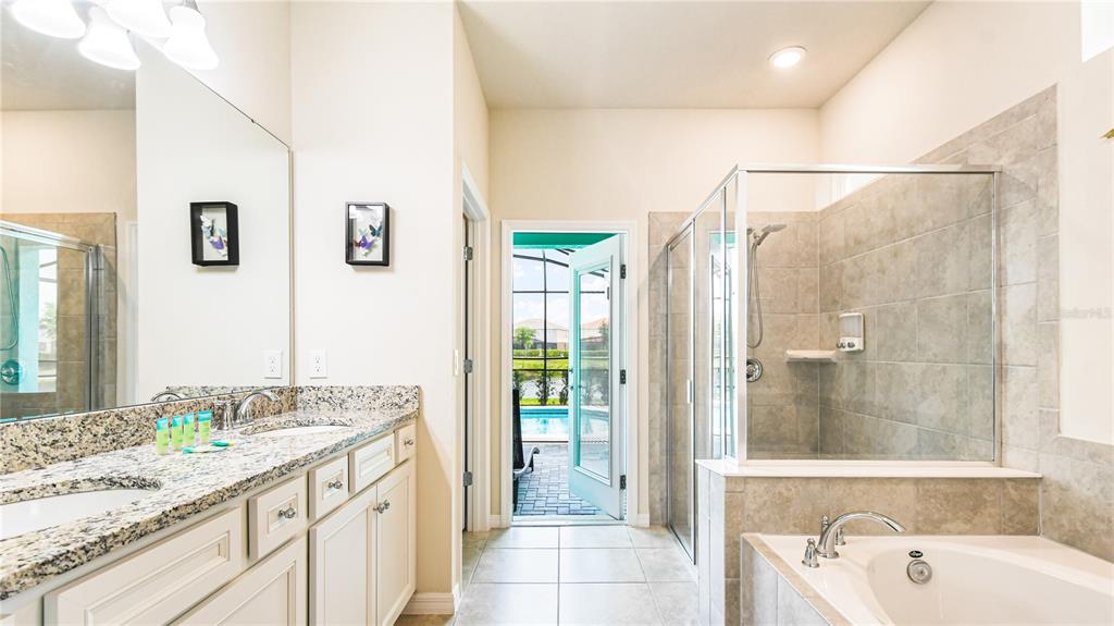 7219 Oakmoss Loop Davenport, FL 33837 - Photo 18 of 54 a bathroom with a granite countertop sink a large mirror and a bathtub