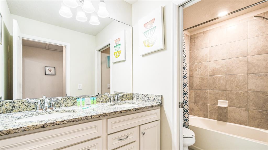 7219 Oakmoss Loop Davenport, FL 33837 - Photo 31 of 54 a bathroom with a granite countertop sink a toilet and bathtub