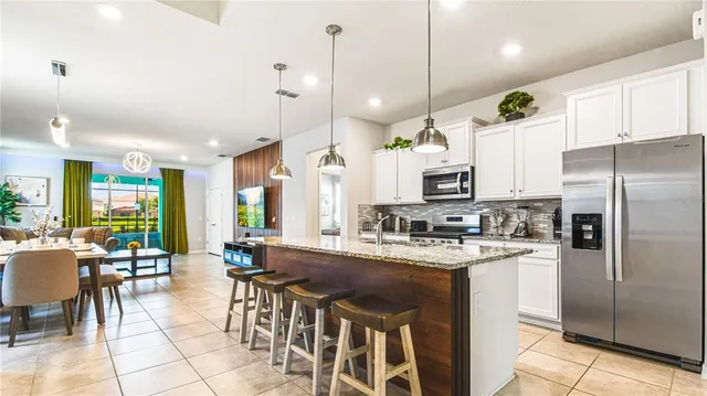 a kitchen with stainless steel appliances kitchen island granite countertop a table chairs and a refrigerator