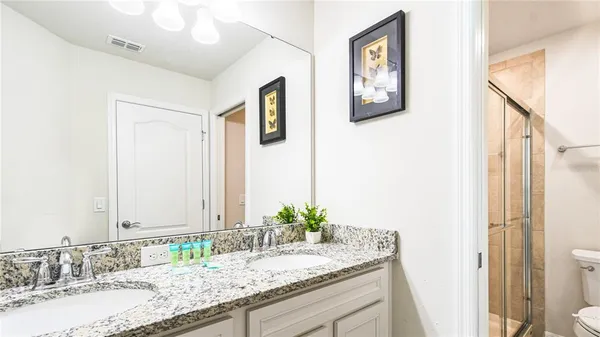 a bathroom with a granite countertop sink a toilet and a mirror