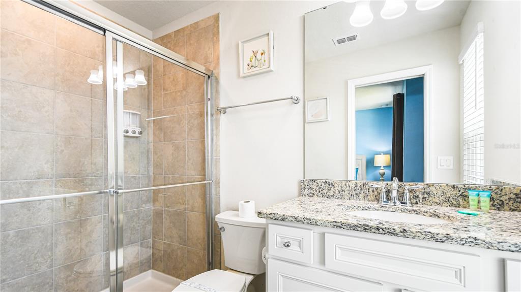 7219 Oakmoss Loop Davenport, FL 33837 - Photo 46 of 54 a bathroom with a granite countertop sink a toilet and a mirror