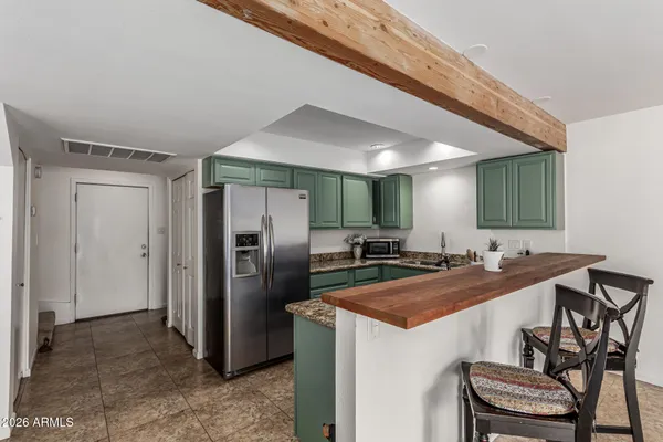 a kitchen with a sink a refrigerator and chairs