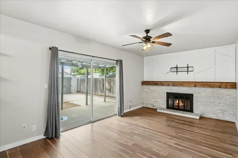 a view of an empty room with wooden floor fireplace and a window