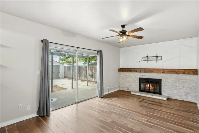 a view of an empty room with wooden floor fireplace and a window