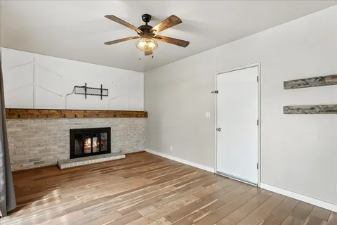 a view of a livingroom with a fireplace a ceiling fan and a table