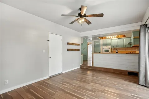 a view of a room with wooden floor and ceiling fan