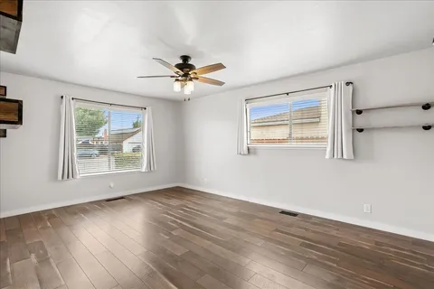 a view of an empty room with wooden floor and a window