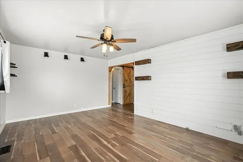a view of empty room with wooden floor and fan