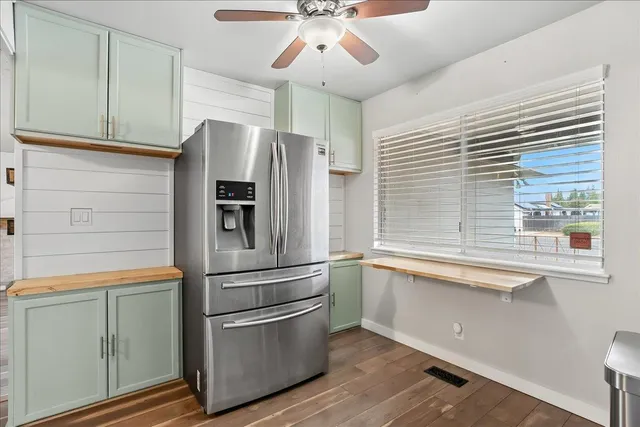 a kitchen with stainless steel appliances a refrigerator a sink and white cabinets