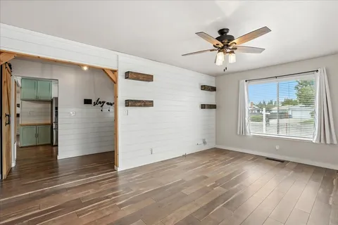 a view of an empty room with wooden floor and a window