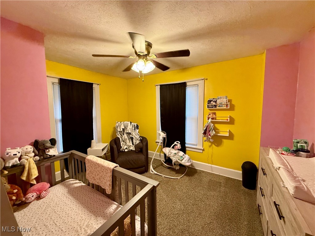 935 Ridge Road Northwest Canton, OH 44703 - Photo 16 of 32 Carpeted bedroom with a textured ceiling, a crib, and a ceiling fan