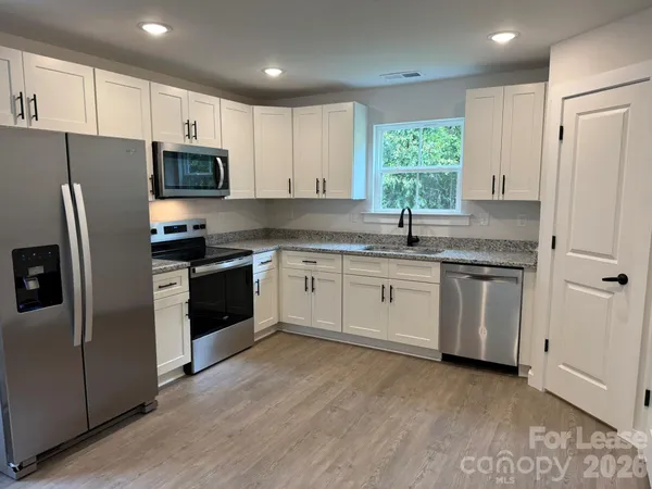 a kitchen with white cabinets stainless steel appliances and window