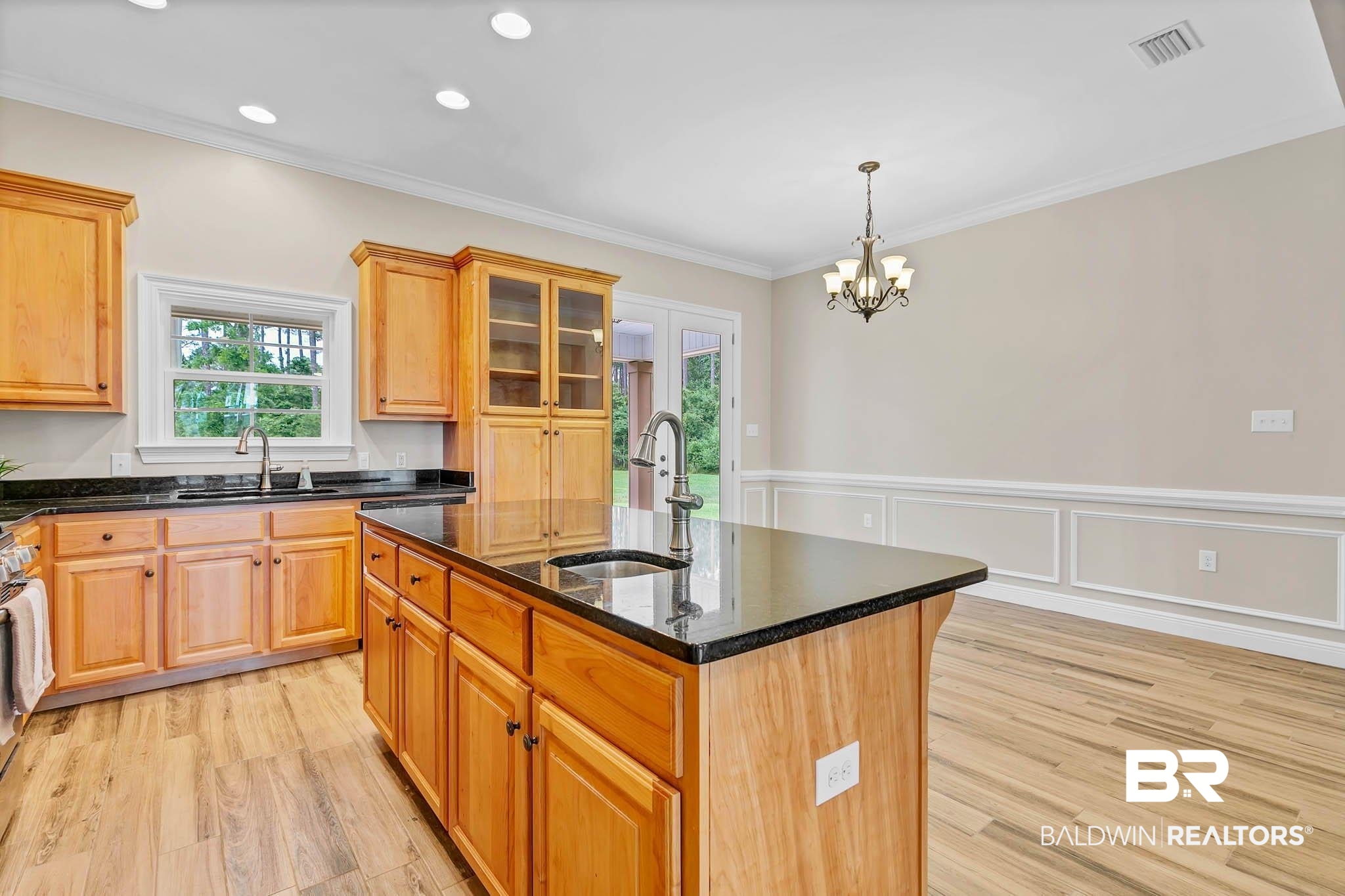8145 Bay View Drive Foley, AL 36535 - Photo 21 of 81 Kitchen with light wood-type flooring, a center island with sink, dark stone countertops, crown molding, and a chandelier