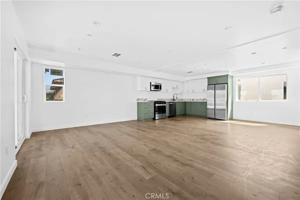 a view of empty room with kitchen and window