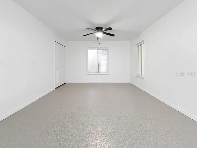an empty room with a window and a ceiling fan