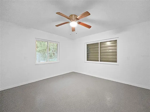 an empty room with windows and fan