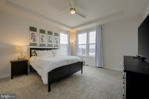 a spacious bedroom with a bed and a flat tv screen on a dresser