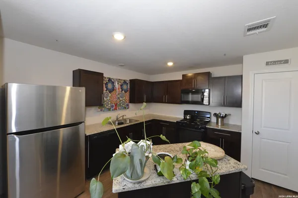 a kitchen with stainless steel appliances kitchen island granite countertop a refrigerator and a sink