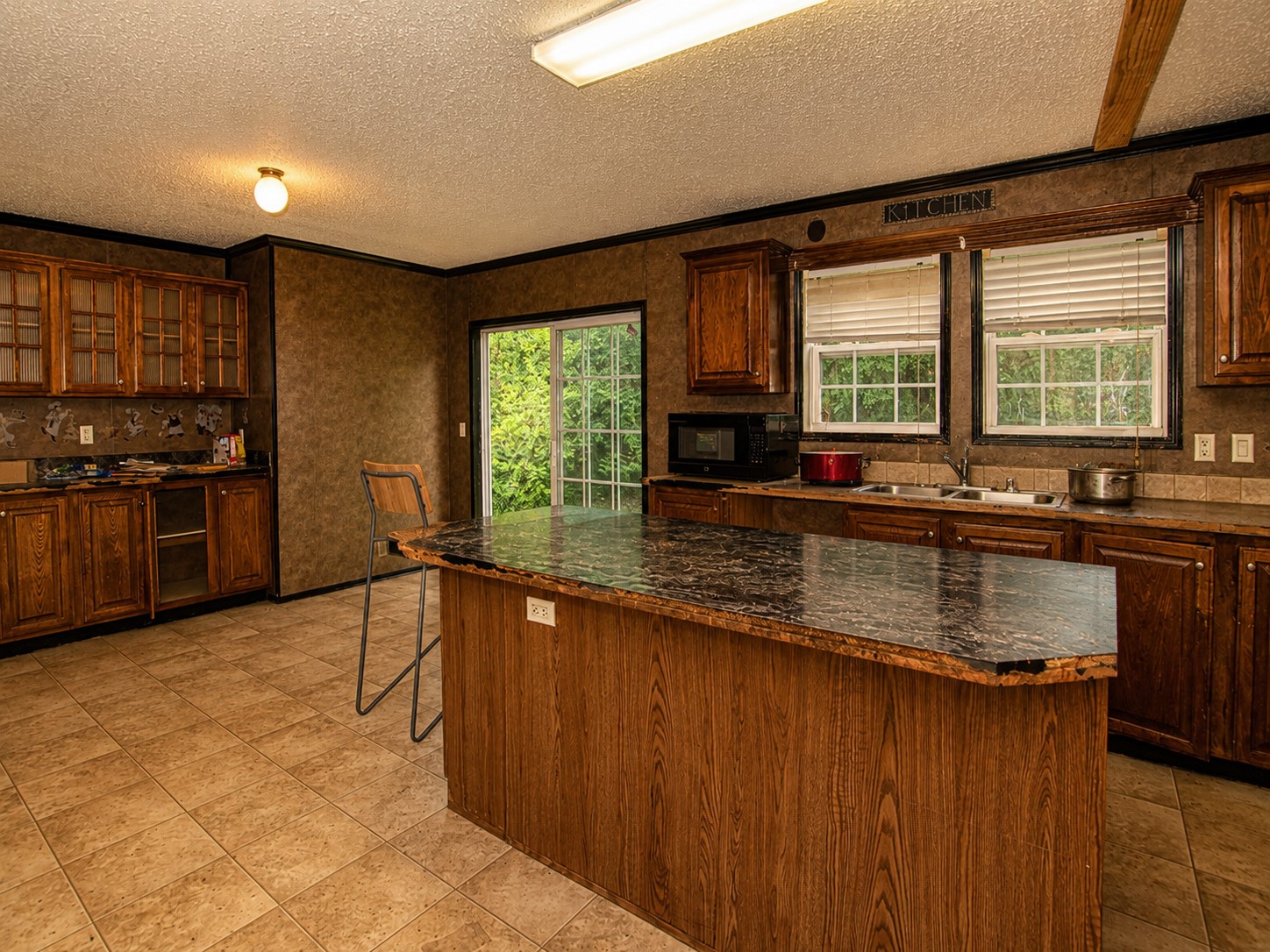 461924 East 1140 Road Sallisaw, OK 74955 - Photo 9 of 29 Kitchen featuring wood-finish cabinetry, a central island with a stone-finish countertop, tile flooring, and a sliding glass door