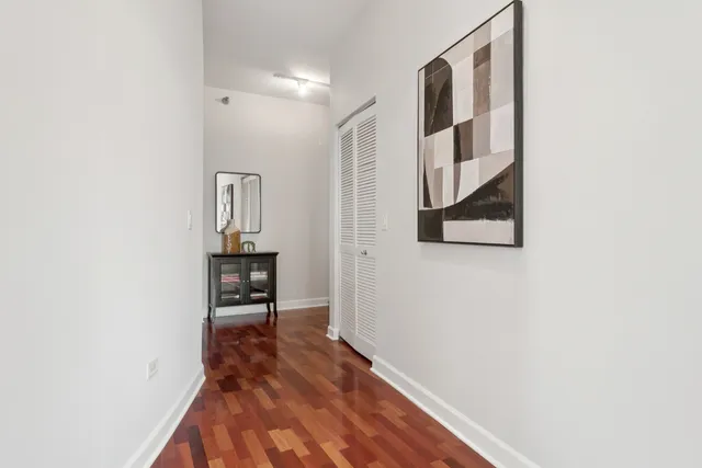 a view of a hallway with wooden floor and a bathroom