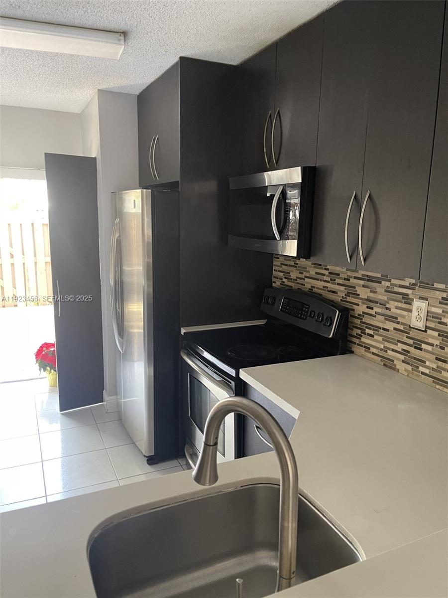 6606 Southwest 131st Path, Unit 1809A Miami, FL 33183 - Photo 12 of 14 a kitchen with a refrigerator and a sink