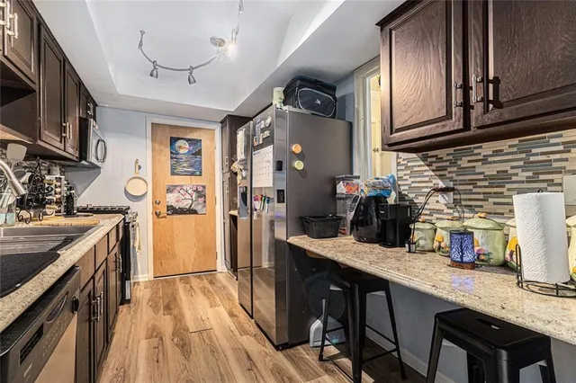 a kitchen with granite countertop a sink appliances cabinets and wooden floor
