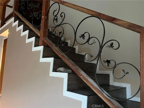 a view of staircase with a metal railing and a chandelier