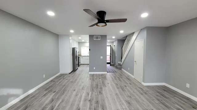 a view of a room with wooden floor and a ceiling fan