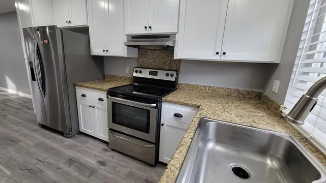 a kitchen with granite countertop white cabinets and stainless steel appliances