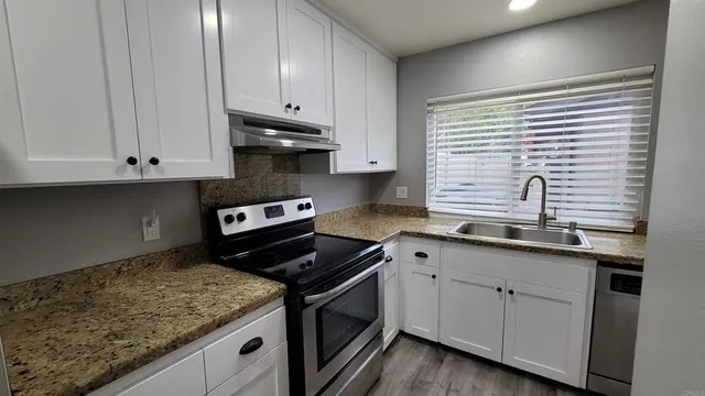 a kitchen with granite countertop white cabinets and a stove