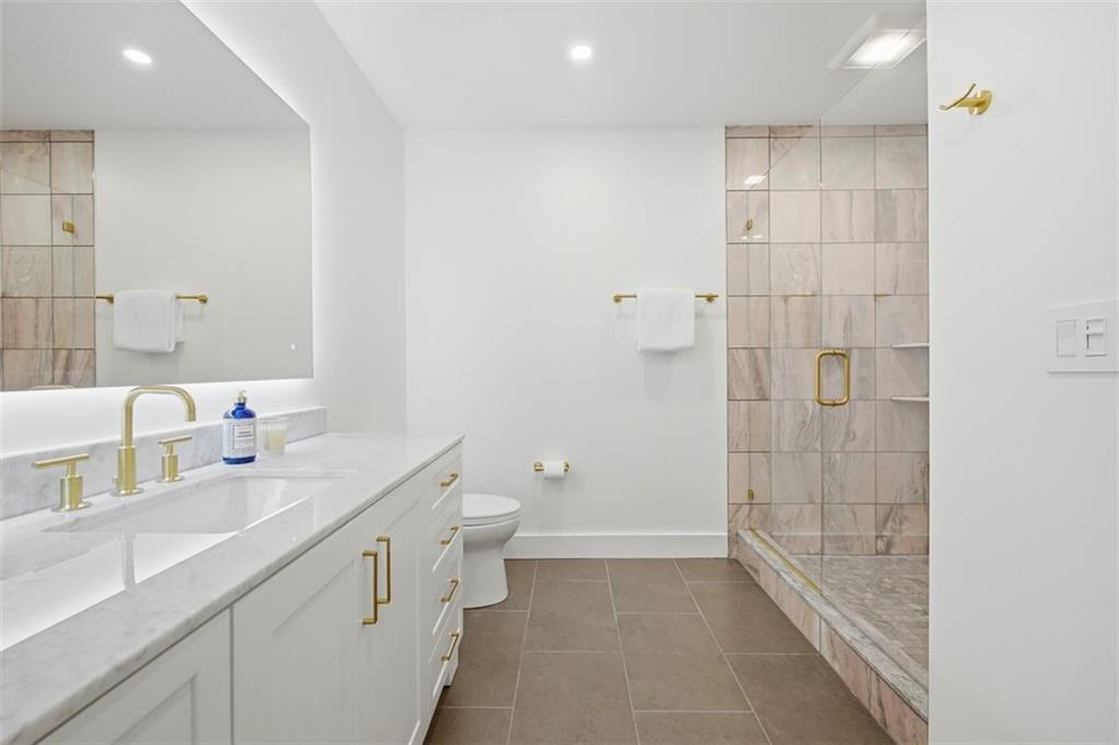 443 Walnut Street Sewickley, PA 15143 - Photo 38 of 50 Clean-lined and calming, the primary bath pairs a marble vanity and hardwired backlit mirrors with warm brass hardware, a Toto toilet, and a glass-enclosed shower finished in natural stone.