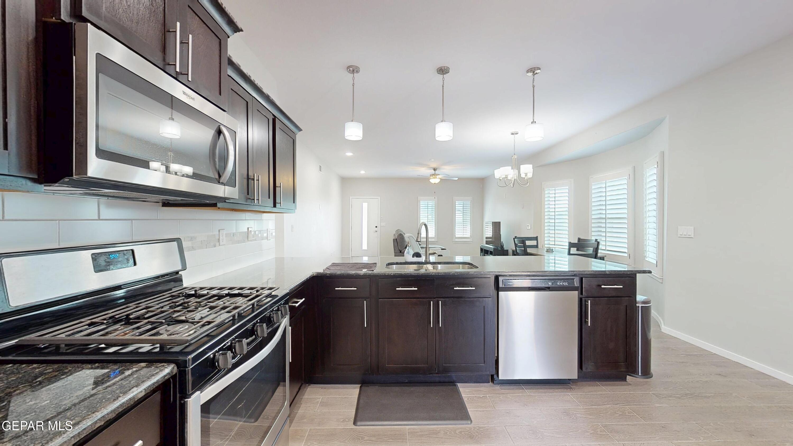 219 Notts Way El Paso, TX 79928 - Photo 12 of 35 a kitchen with stainless steel appliances granite countertop a stove a sink and a microwave