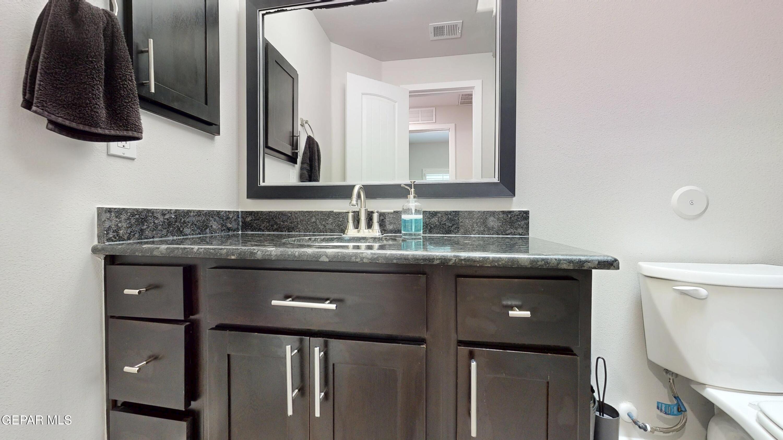219 Notts Way El Paso, TX 79928 - Photo 31 of 35 a bathroom with a granite countertop sink a toilet and a mirror